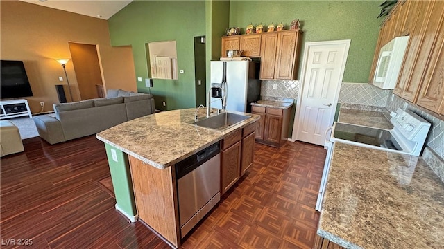 kitchen featuring sink, an island with sink, backsplash, high vaulted ceiling, and appliances with stainless steel finishes