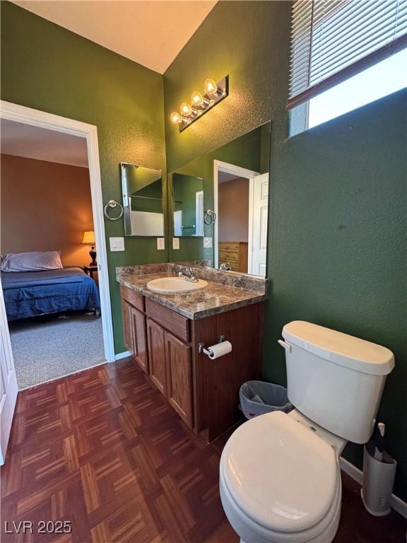 bathroom featuring parquet floors, vanity, and toilet