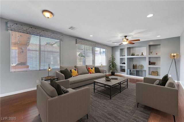 living room featuring dark hardwood / wood-style flooring, ceiling fan, and built in shelves