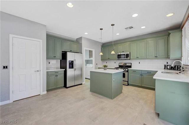 kitchen featuring pendant lighting, green cabinetry, a kitchen island, appliances with stainless steel finishes, and sink