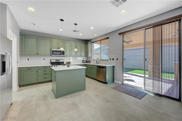 kitchen with stainless steel appliances, a kitchen island, green cabinets, and pendant lighting