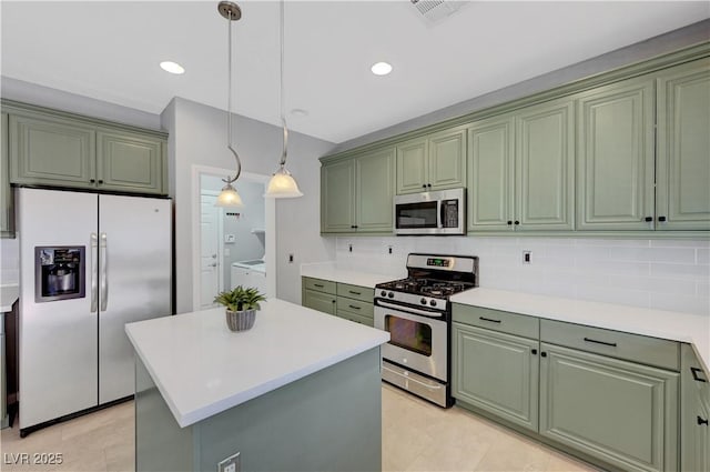 kitchen with a kitchen island, stainless steel appliances, pendant lighting, and green cabinets