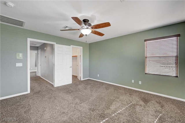 unfurnished bedroom with ceiling fan, a spacious closet, and carpet floors