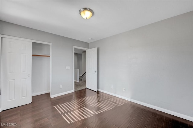 unfurnished bedroom with dark wood-type flooring and a closet