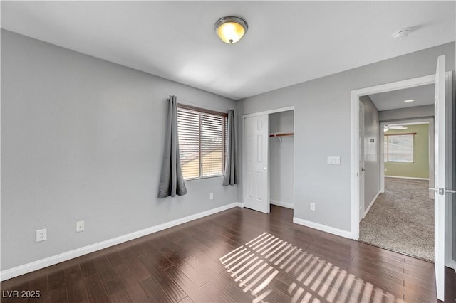 unfurnished bedroom with a closet, multiple windows, and dark wood-type flooring