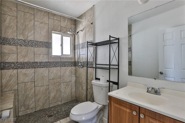 bathroom featuring tiled shower, vanity, and toilet