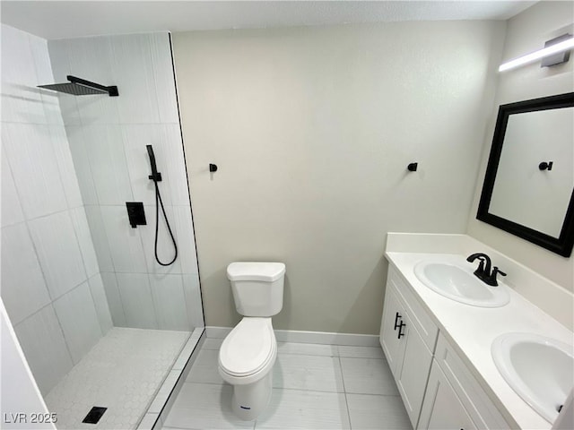 bathroom featuring toilet, a tile shower, vanity, and tile patterned flooring