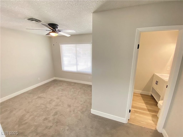 spare room featuring a textured ceiling, ceiling fan, and light colored carpet