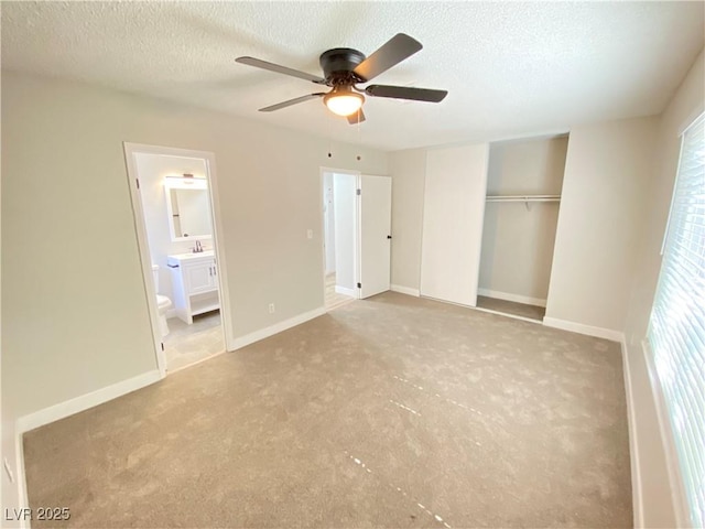 unfurnished bedroom with ceiling fan, ensuite bathroom, a closet, and a textured ceiling