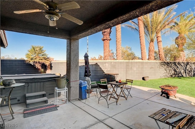 view of patio / terrace with ceiling fan, a hot tub, and an outdoor fire pit