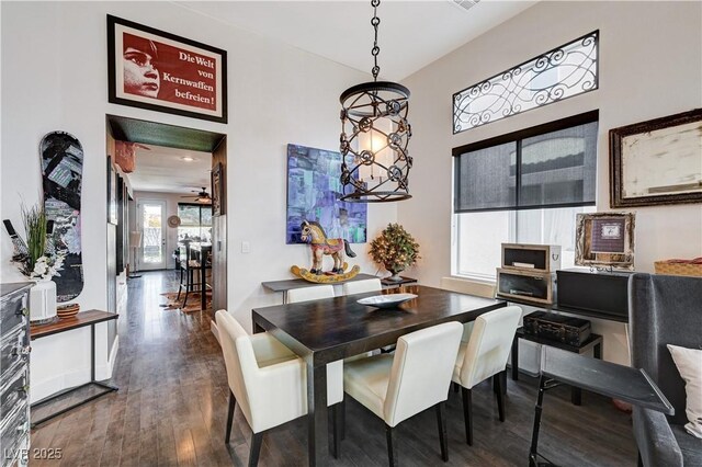 dining area with ceiling fan with notable chandelier and dark hardwood / wood-style floors