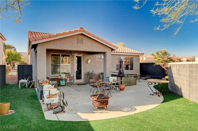 back of property featuring a fire pit, a yard, and a patio