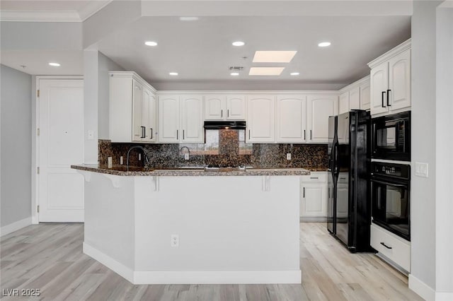 kitchen with kitchen peninsula, white cabinets, and black appliances