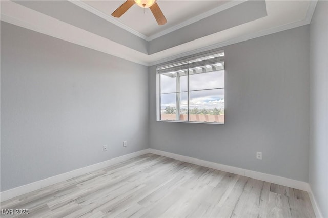 spare room with ceiling fan, light wood-type flooring, ornamental molding, and a tray ceiling