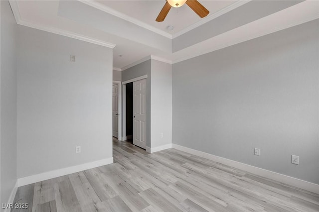 spare room with ornamental molding, ceiling fan, light wood-type flooring, and a raised ceiling