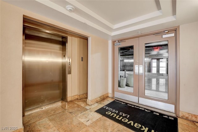 doorway featuring elevator and a tray ceiling