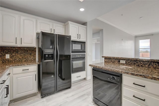 kitchen featuring dark stone counters, ornamental molding, black appliances, and white cabinetry