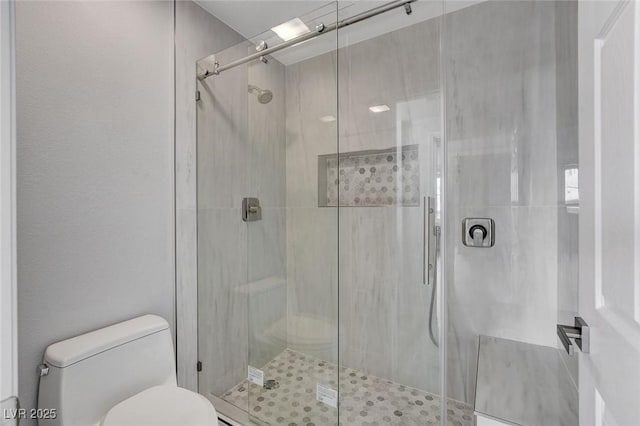 bathroom with a shower with door and toilet