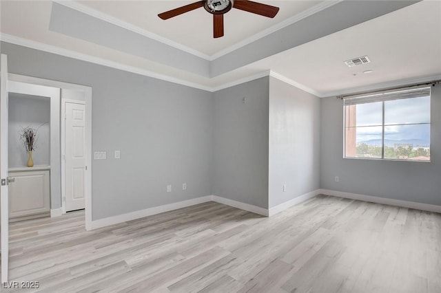 unfurnished room with a raised ceiling, ceiling fan, ornamental molding, and light hardwood / wood-style floors