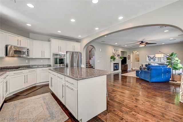 kitchen with dark stone counters, stainless steel appliances, white cabinetry, and a center island