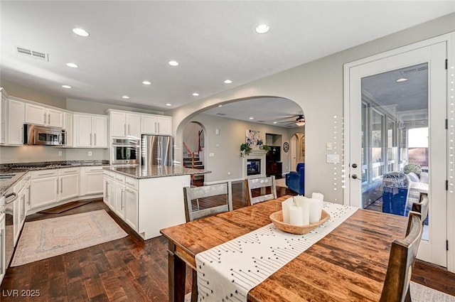 kitchen featuring dark stone counters, stainless steel appliances, white cabinetry, and a kitchen island