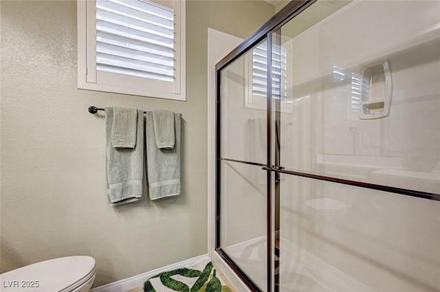 bathroom with a shower with door and toilet