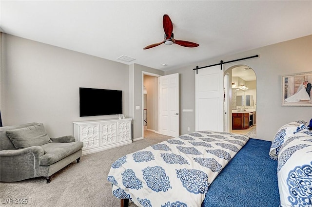 carpeted bedroom featuring connected bathroom, ceiling fan, and a barn door