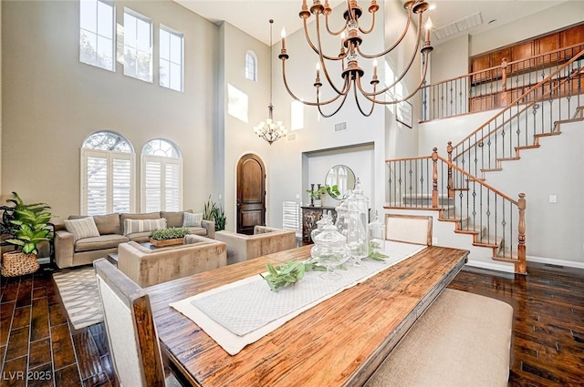 dining room with dark hardwood / wood-style flooring, a towering ceiling, and a chandelier