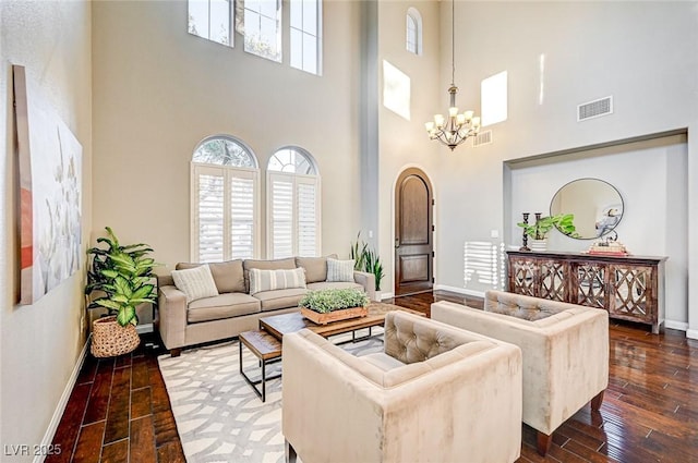 living room with a towering ceiling, a notable chandelier, and dark hardwood / wood-style flooring