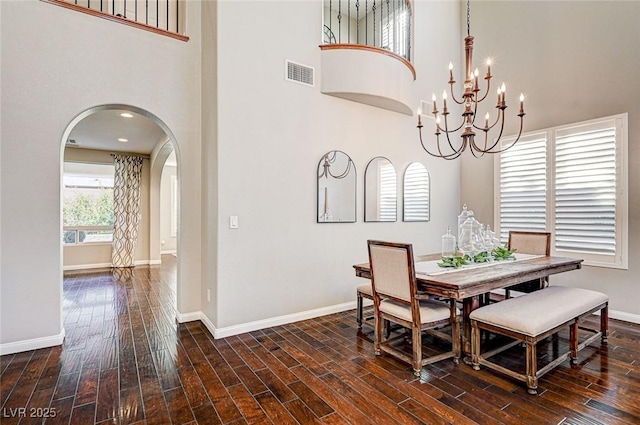 dining room featuring a high ceiling, dark wood-type flooring, and an inviting chandelier