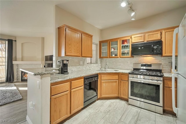 kitchen featuring kitchen peninsula, light stone countertops, and black appliances