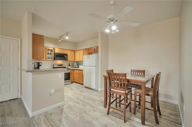 kitchen with stainless steel stove, white fridge, light stone counters, ceiling fan, and backsplash