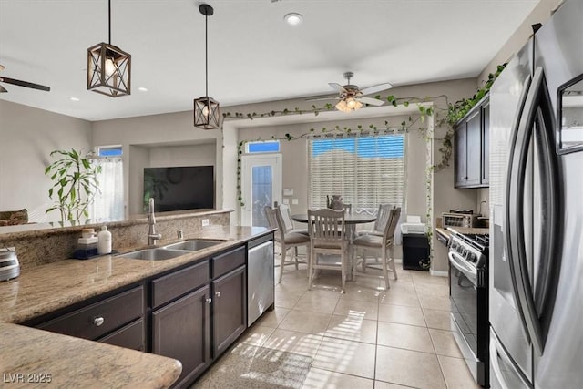 kitchen featuring hanging light fixtures, stainless steel appliances, light tile patterned floors, dark brown cabinets, and sink