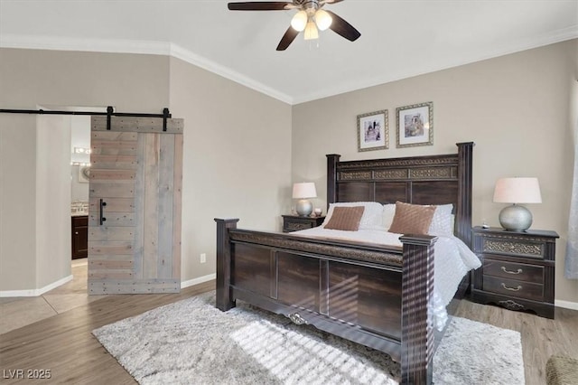 bedroom with ornamental molding, ceiling fan, a barn door, and light hardwood / wood-style floors