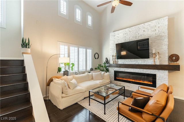 living room featuring a high ceiling, a fireplace, and ceiling fan