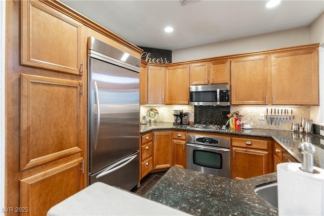 kitchen featuring dark stone counters, appliances with stainless steel finishes, and tasteful backsplash