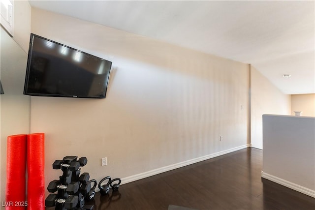 exercise room featuring vaulted ceiling and dark hardwood / wood-style floors