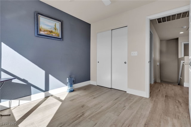 unfurnished bedroom featuring light wood-type flooring, ceiling fan, and a closet