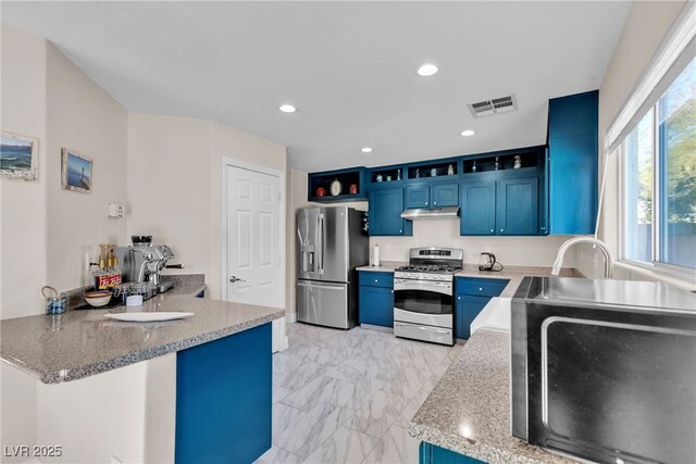 kitchen with blue cabinets, light stone counters, kitchen peninsula, and appliances with stainless steel finishes