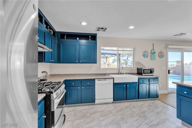 kitchen featuring light stone counters, appliances with stainless steel finishes, blue cabinetry, and sink