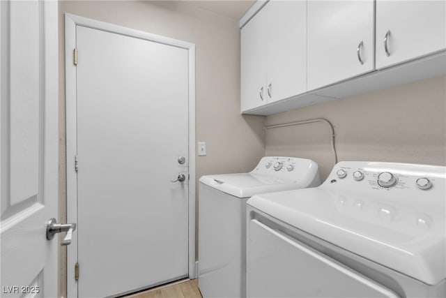 clothes washing area with washing machine and clothes dryer, light wood-type flooring, and cabinets