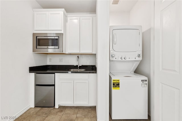 laundry room featuring sink, light tile patterned floors, and stacked washer / drying machine