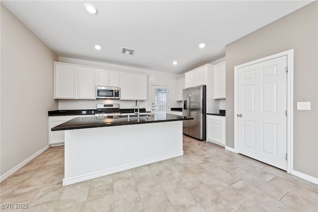 kitchen with white cabinets, stainless steel appliances, and a center island with sink