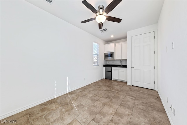 kitchen featuring sink, white cabinets, stainless steel microwave, and ceiling fan