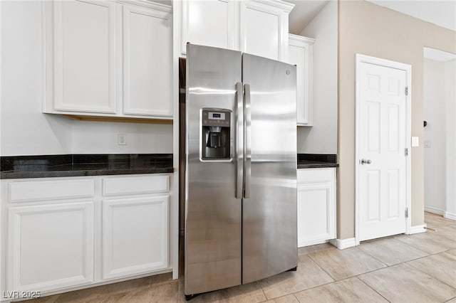 kitchen featuring dark stone counters, white cabinetry, light tile patterned flooring, and stainless steel refrigerator with ice dispenser