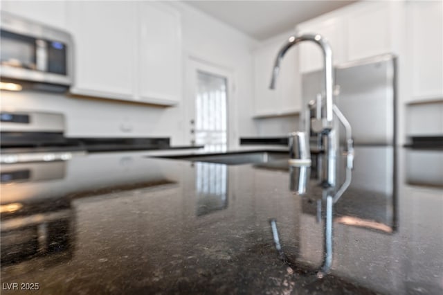 interior details with white cabinets and dark stone counters