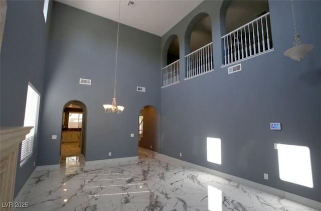 unfurnished living room with a towering ceiling and a chandelier