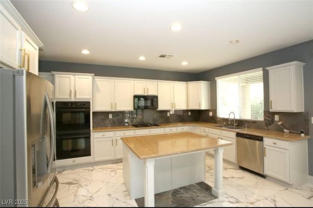 kitchen featuring black appliances, a center island, light stone counters, decorative backsplash, and white cabinets