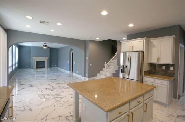 kitchen featuring stainless steel appliances, tasteful backsplash, a kitchen island, white cabinets, and ceiling fan