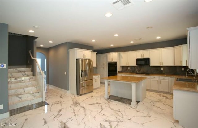 kitchen featuring black appliances, white cabinetry, a center island, and sink